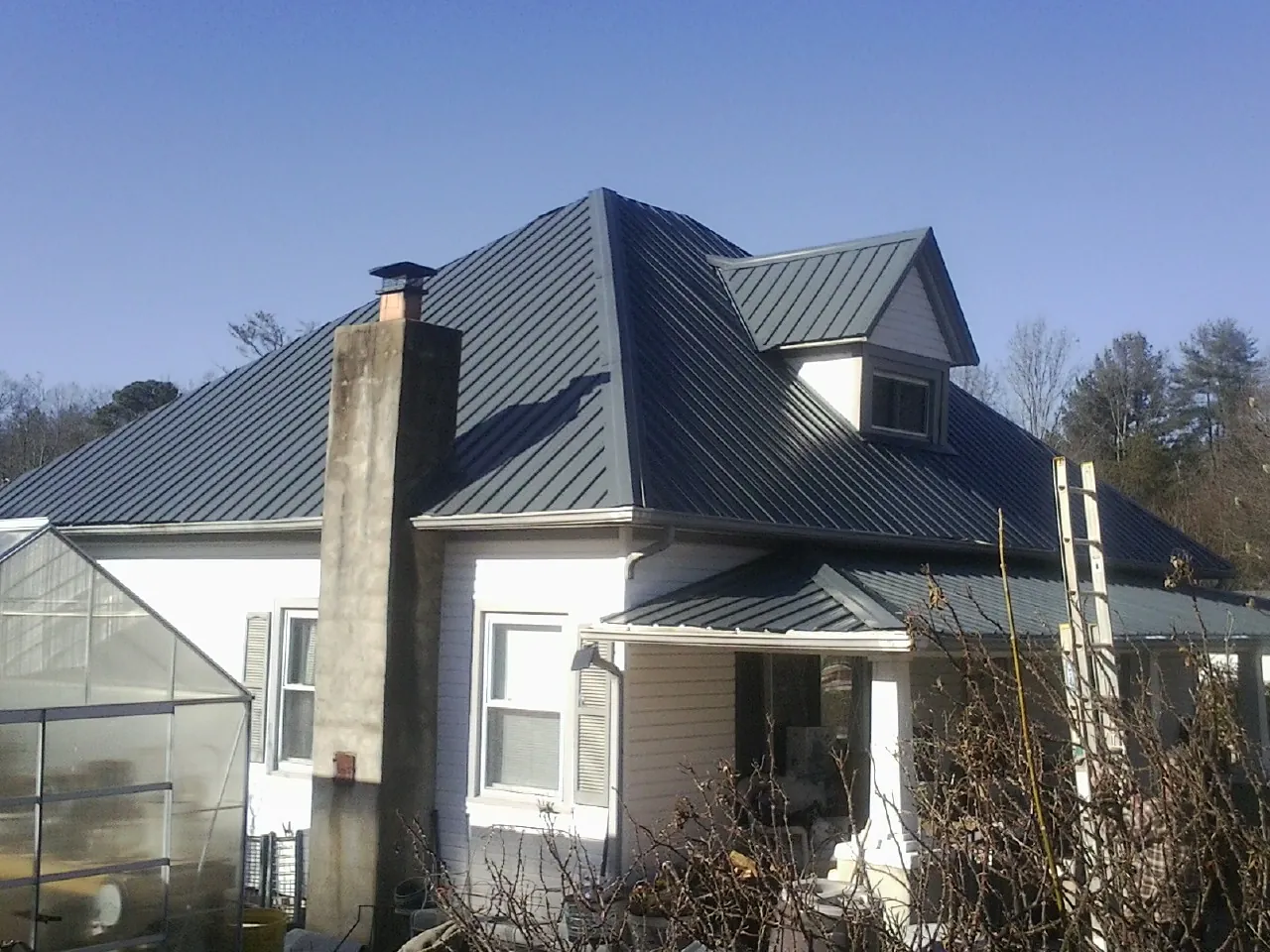 Dark blue standing seam metal roof on a white farmhouse with dormer — Slate & Tile Roof Repair by Roofing Brothers in Quaker City