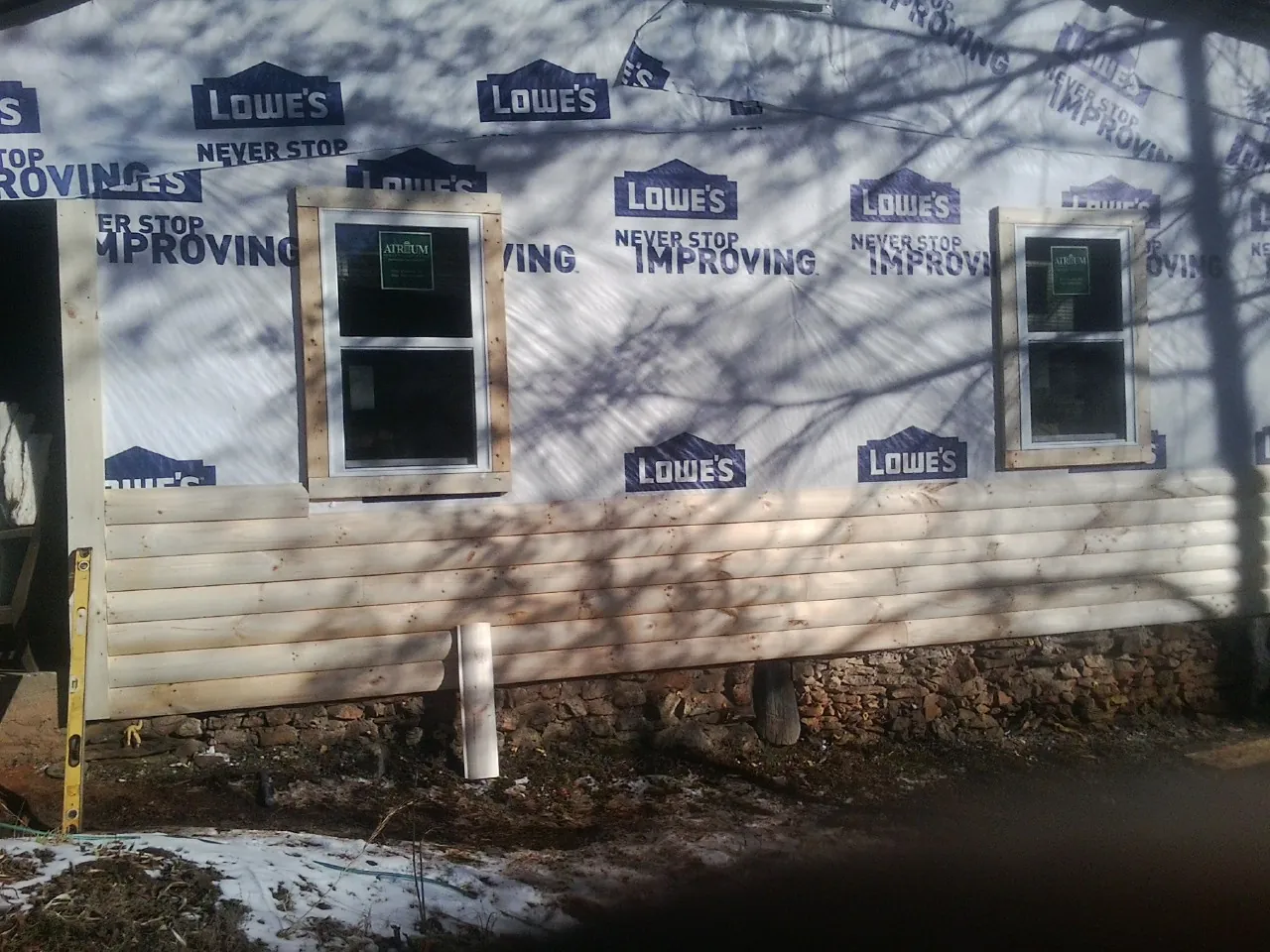 House wrap and new log siding going up on an exterior wall in Quaker City