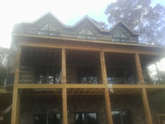 Dormers and porch framing on a large log home under construction — Roof Coating work by our crew in Quaker City