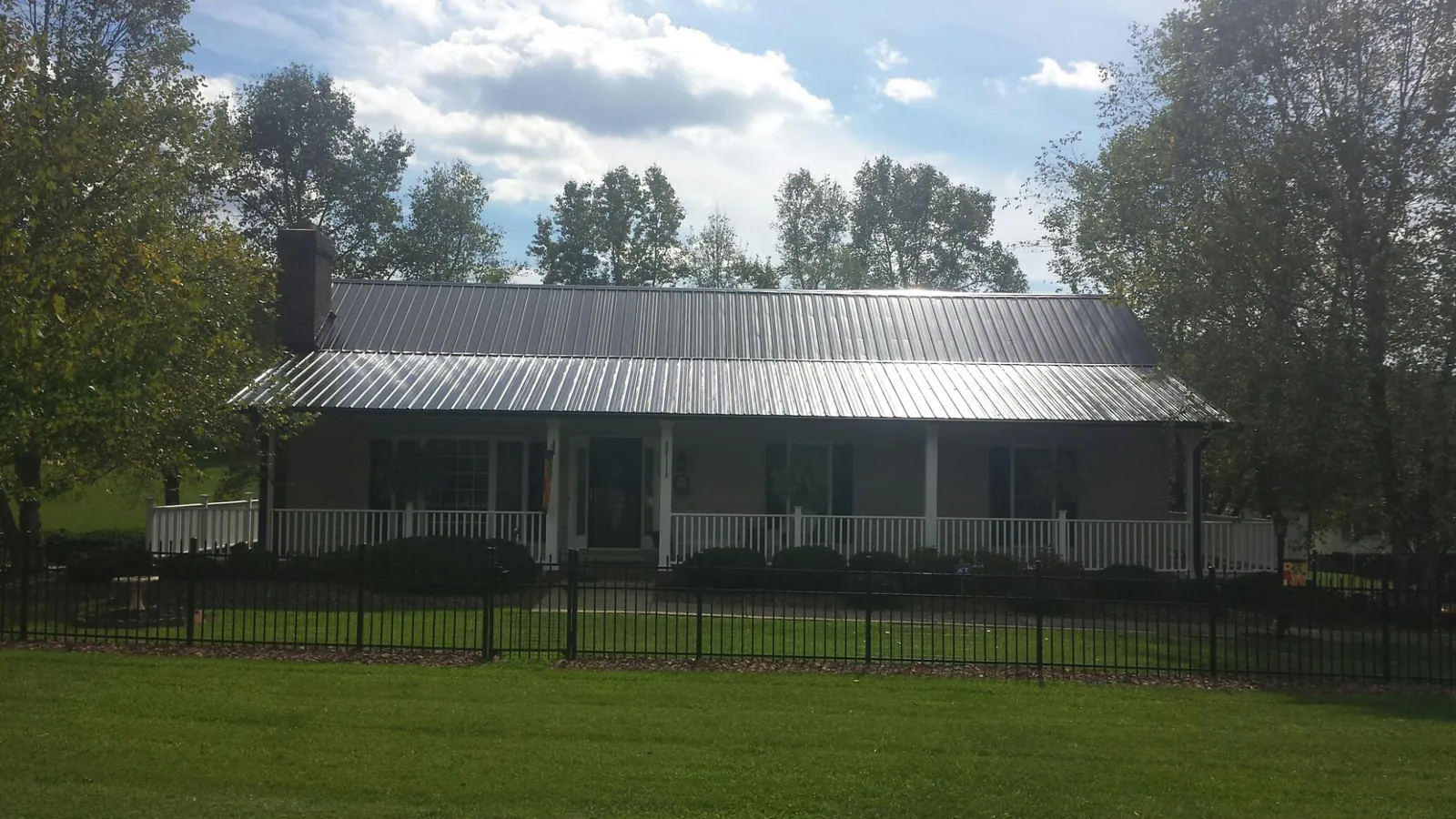 Gray metal roof on a brick ranch with a full width front porch — Gutter Guard Installation work by our crew in Quaker City