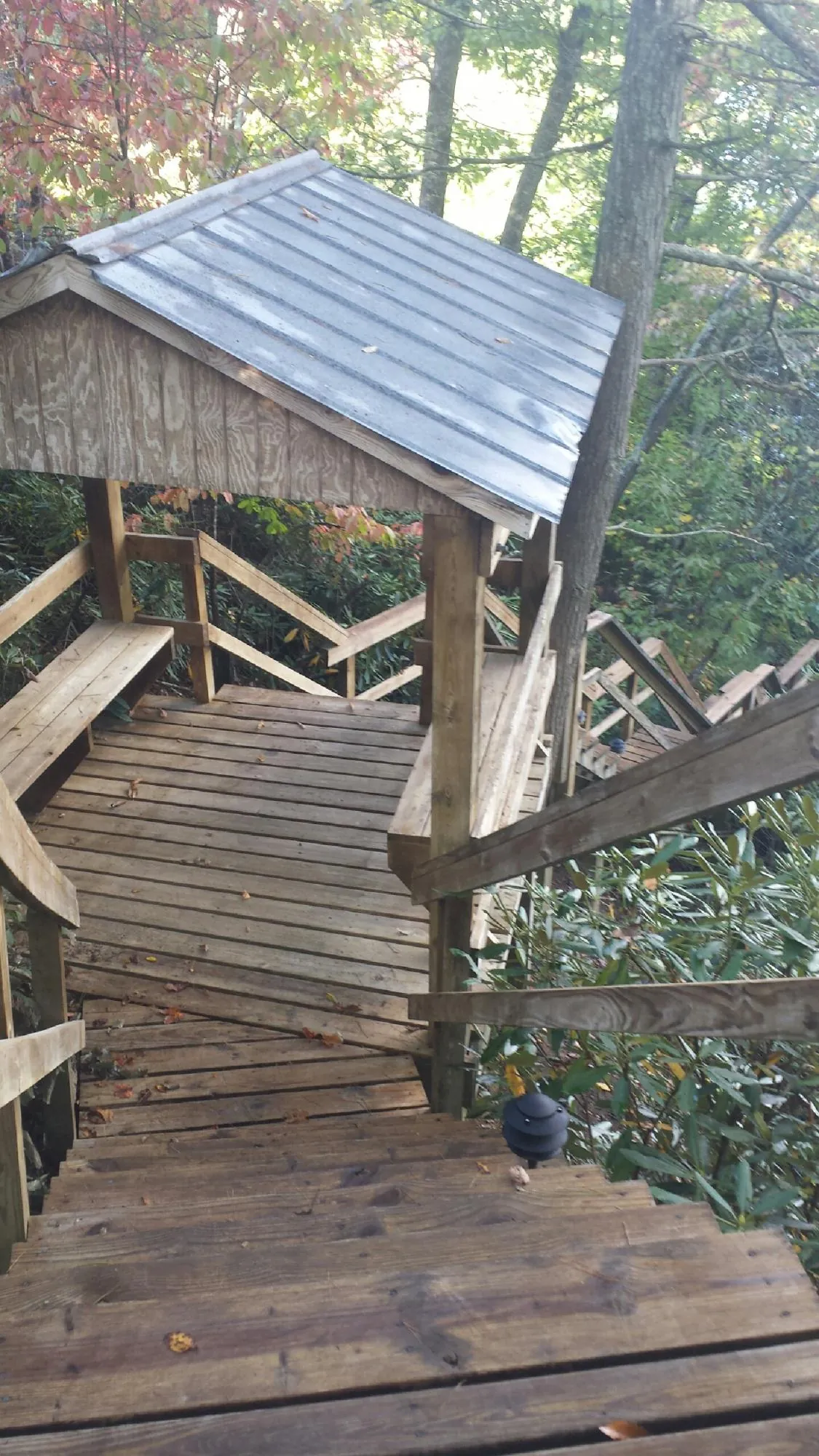 Metal roofed shelter over wooden steps on a wooded walkway — Skylight Repair & Installation work by our crew in Quaker City