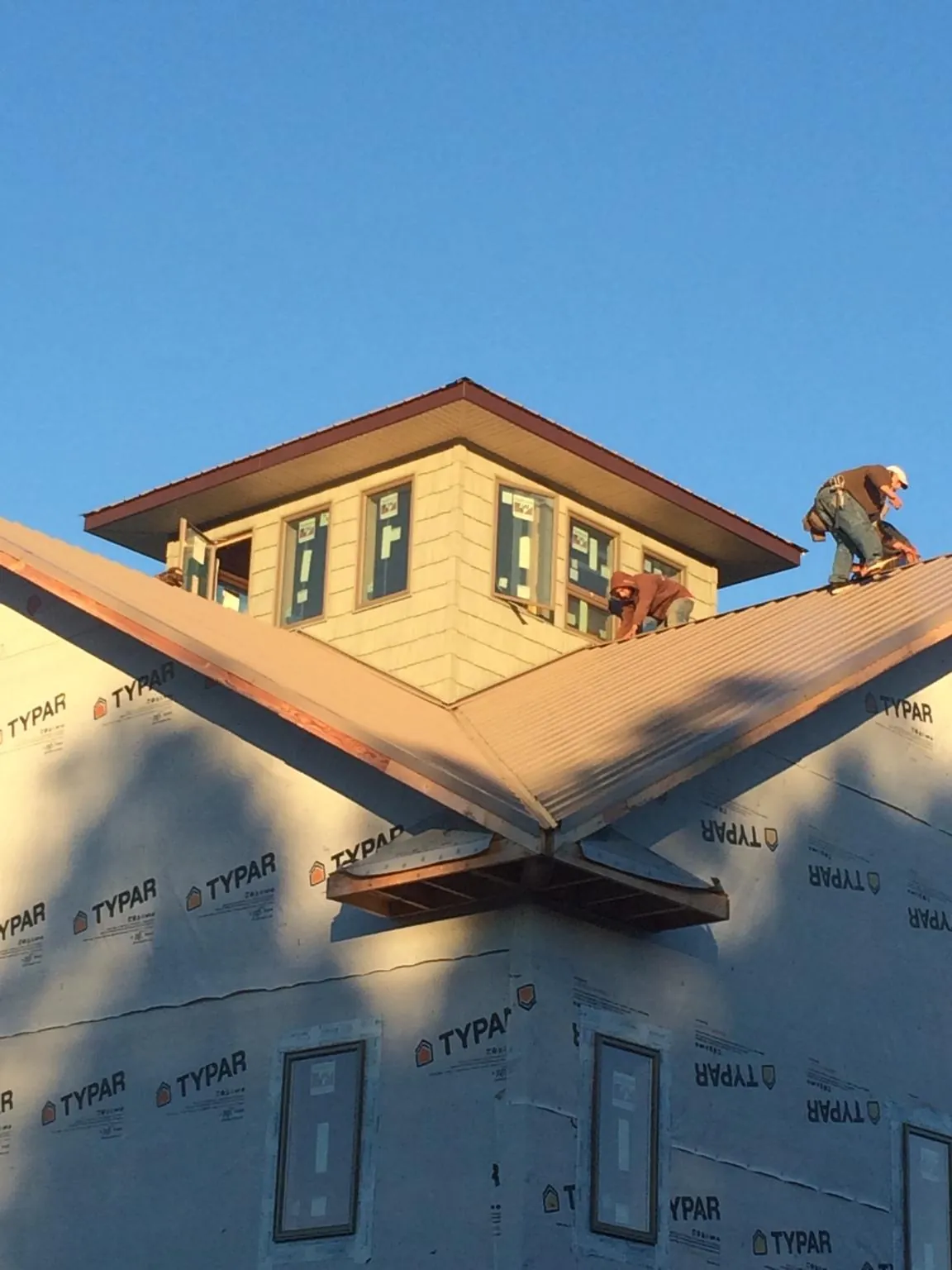 Roofers working around a rooftop cupola on a new metal roof at sunset — Roof Waterproofing in Quaker City by Roofing Brothers